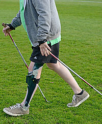 Erwachsener Patient mit Lähmung der Muskeln Muskulatur im Bein nach inkompletter Querschnittlähmung Paraplegie Rückenmarkläsion beim Gehen mit Hilfsmittel Orthese mit elektrisch elektronisch Standphasensicherung Orthesengelenk KAFO